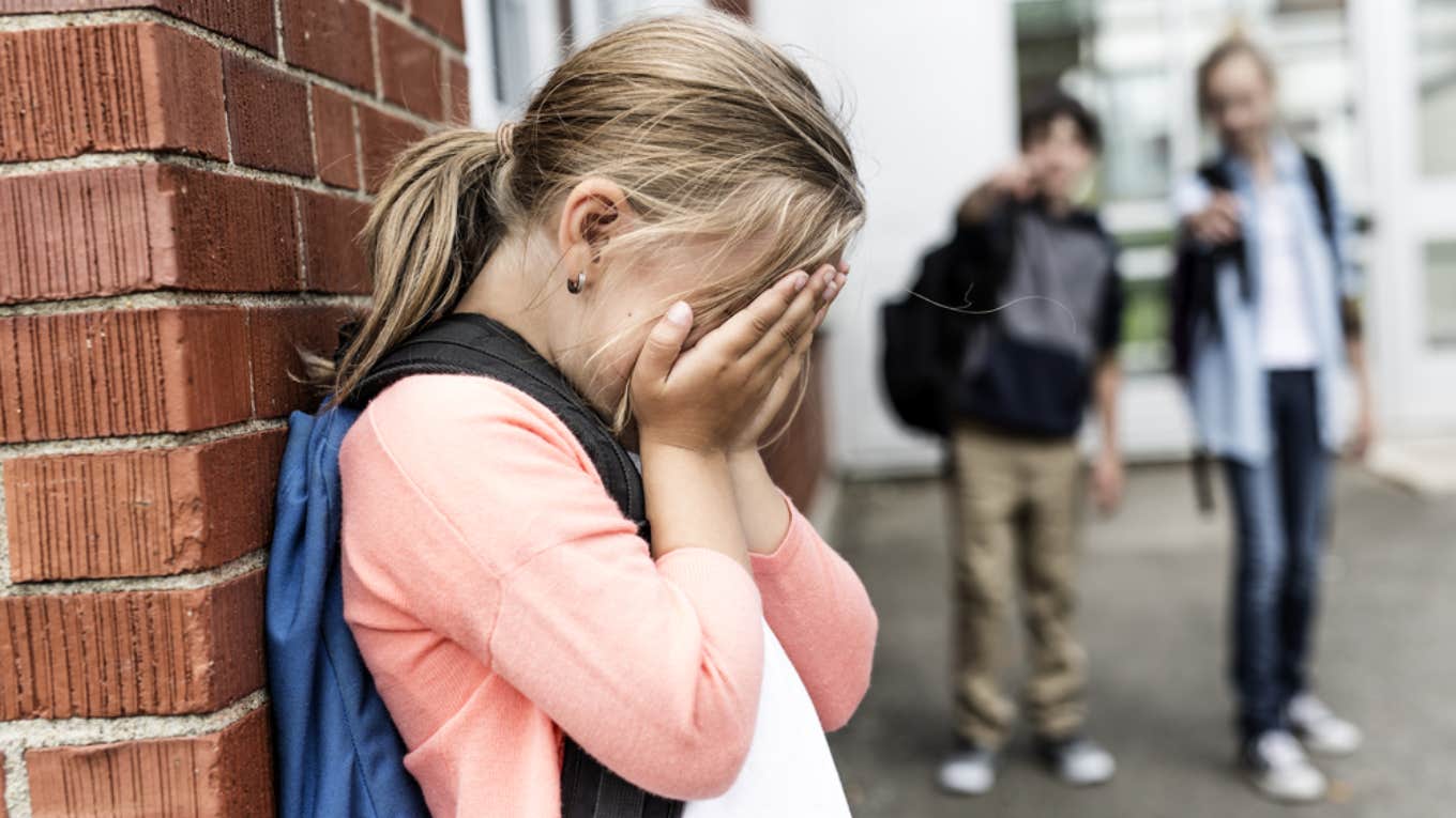 little girl crying while kids point at her