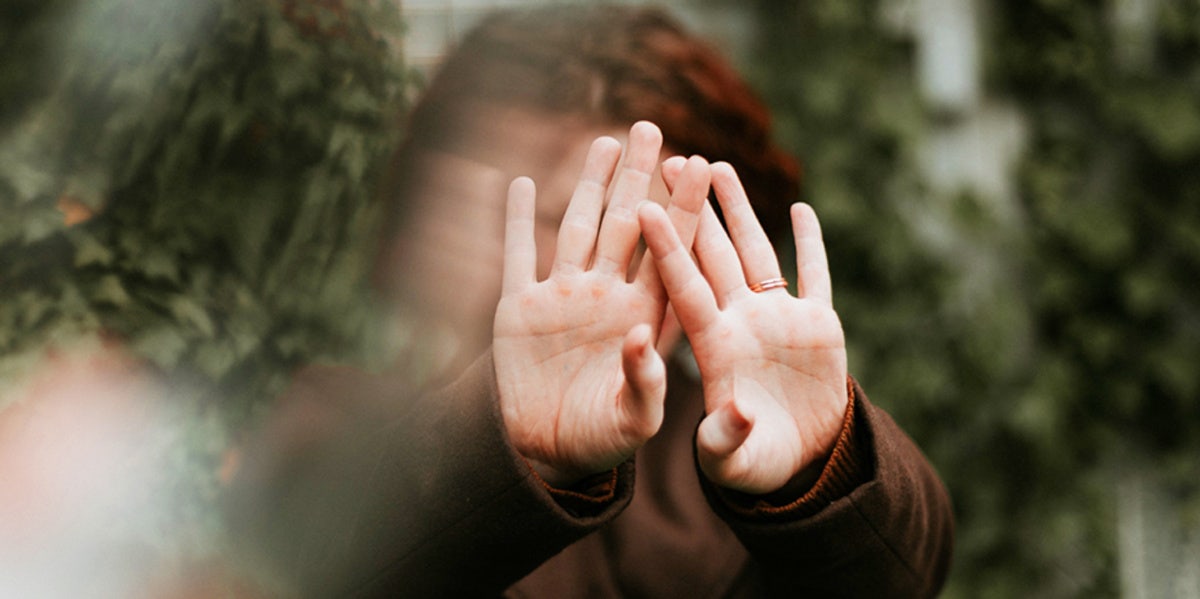 woman with hands up in front of face