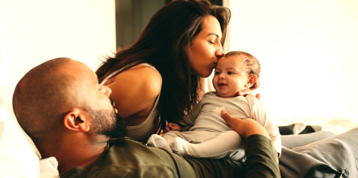 man woman and baby happy in bed