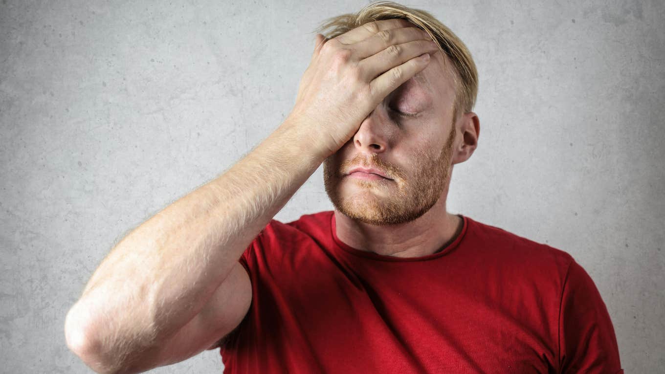 portrait of worried man in red shirt holding his hand to his forehead