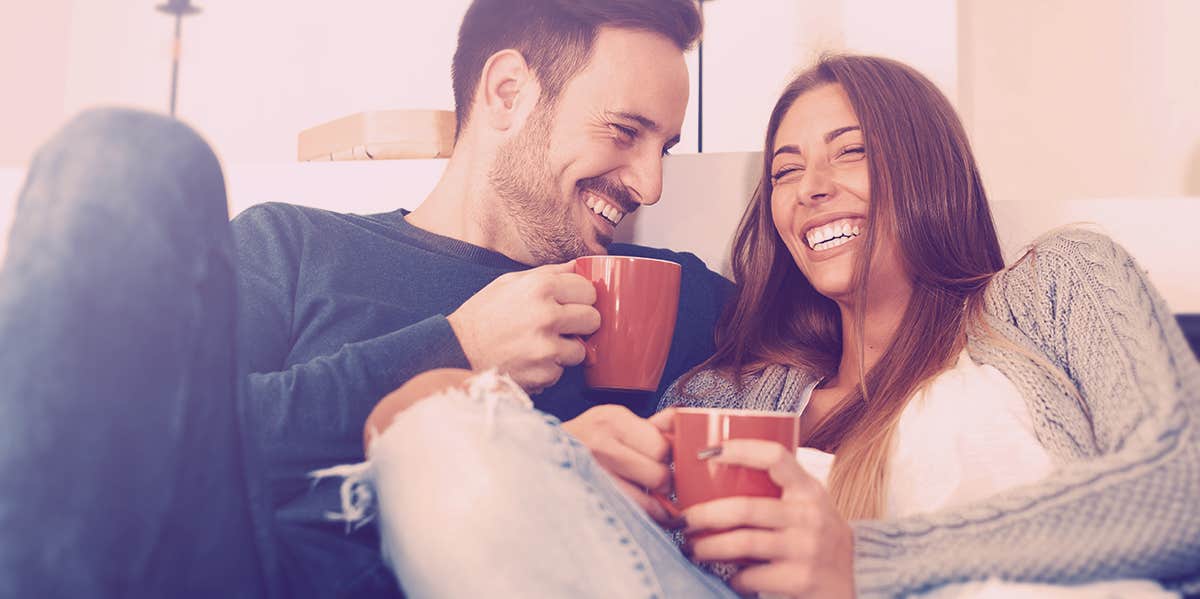 couple smiling at each other, sitting on couch