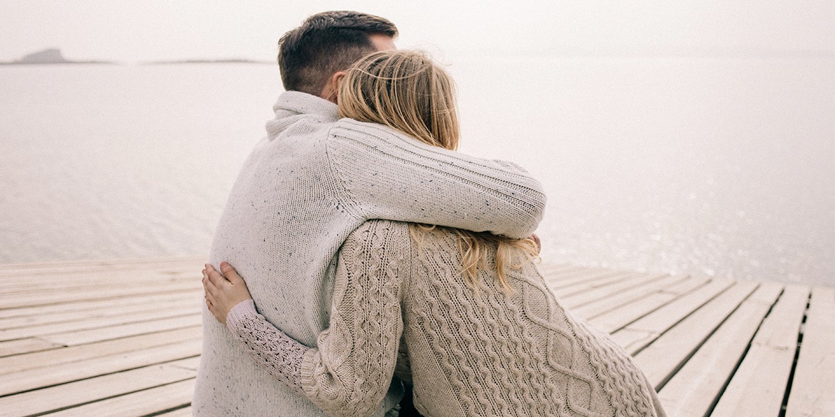 man and woman in sweaters embracing 