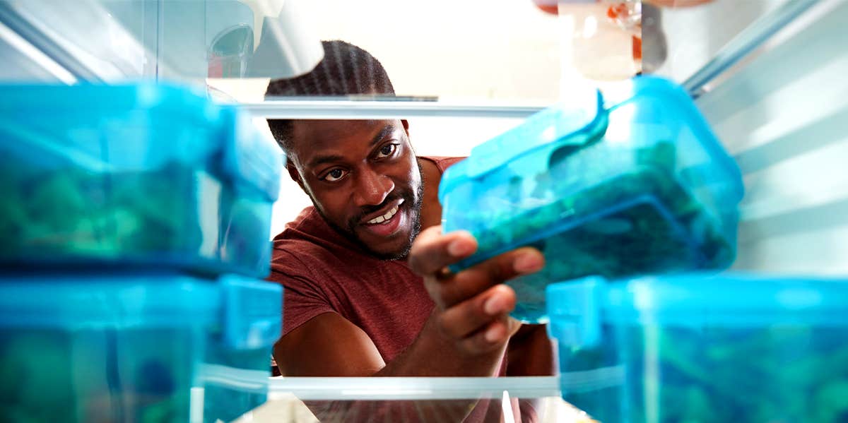 man meal prepping putting food in the fridge