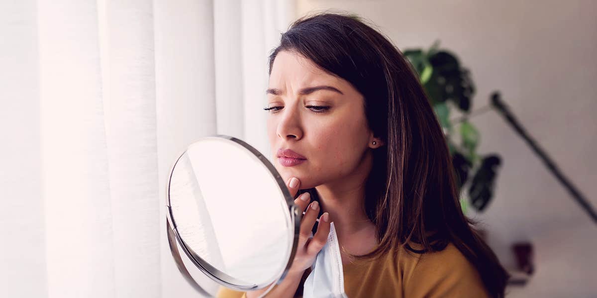 woman looking at her face in the mirror
