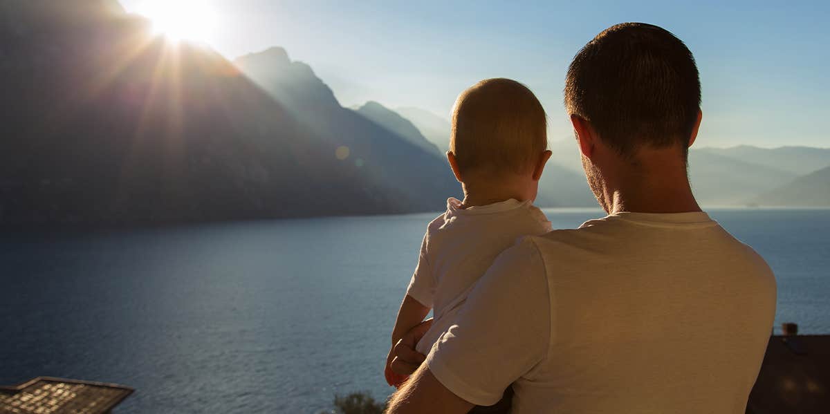 father holding baby looking at water