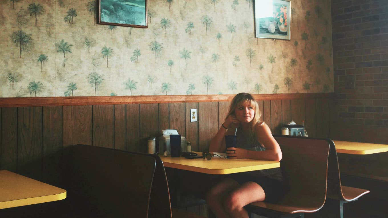 Young girl sitting at diner, upset