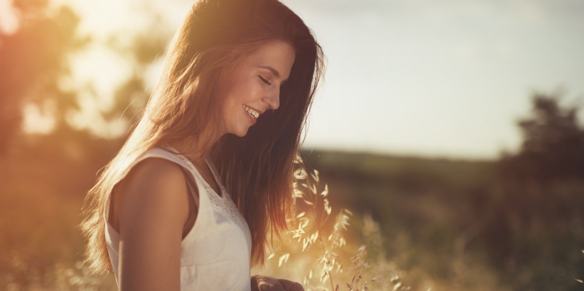 woman in a field of grass at sunset