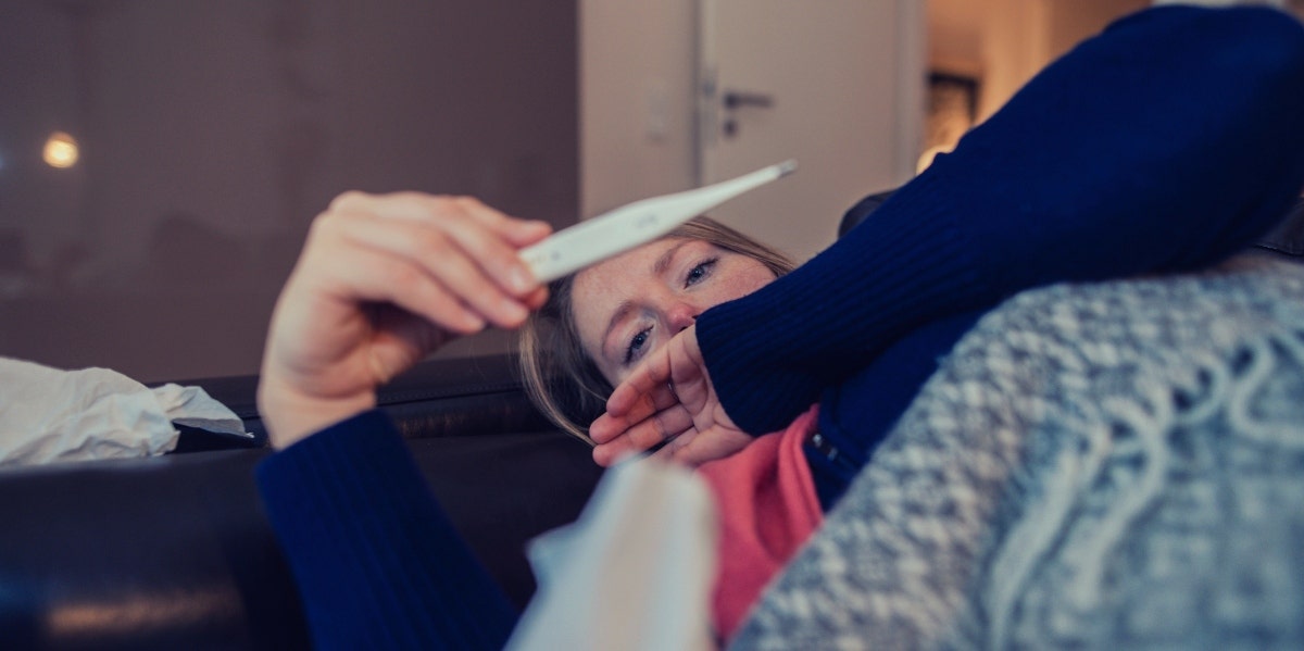 sick woman checking her temperature