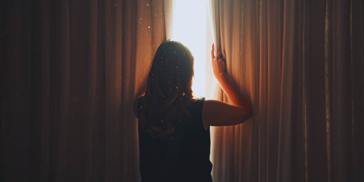 woman opening curtains