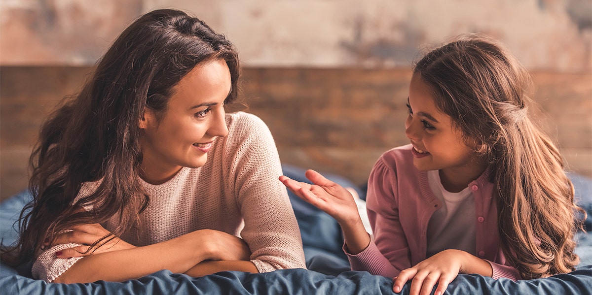 mom and daughter talking together on bed