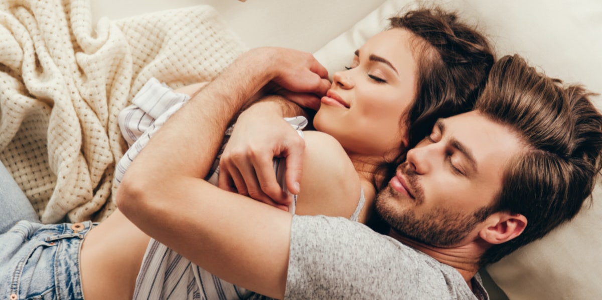 man and woman cuddling in bed