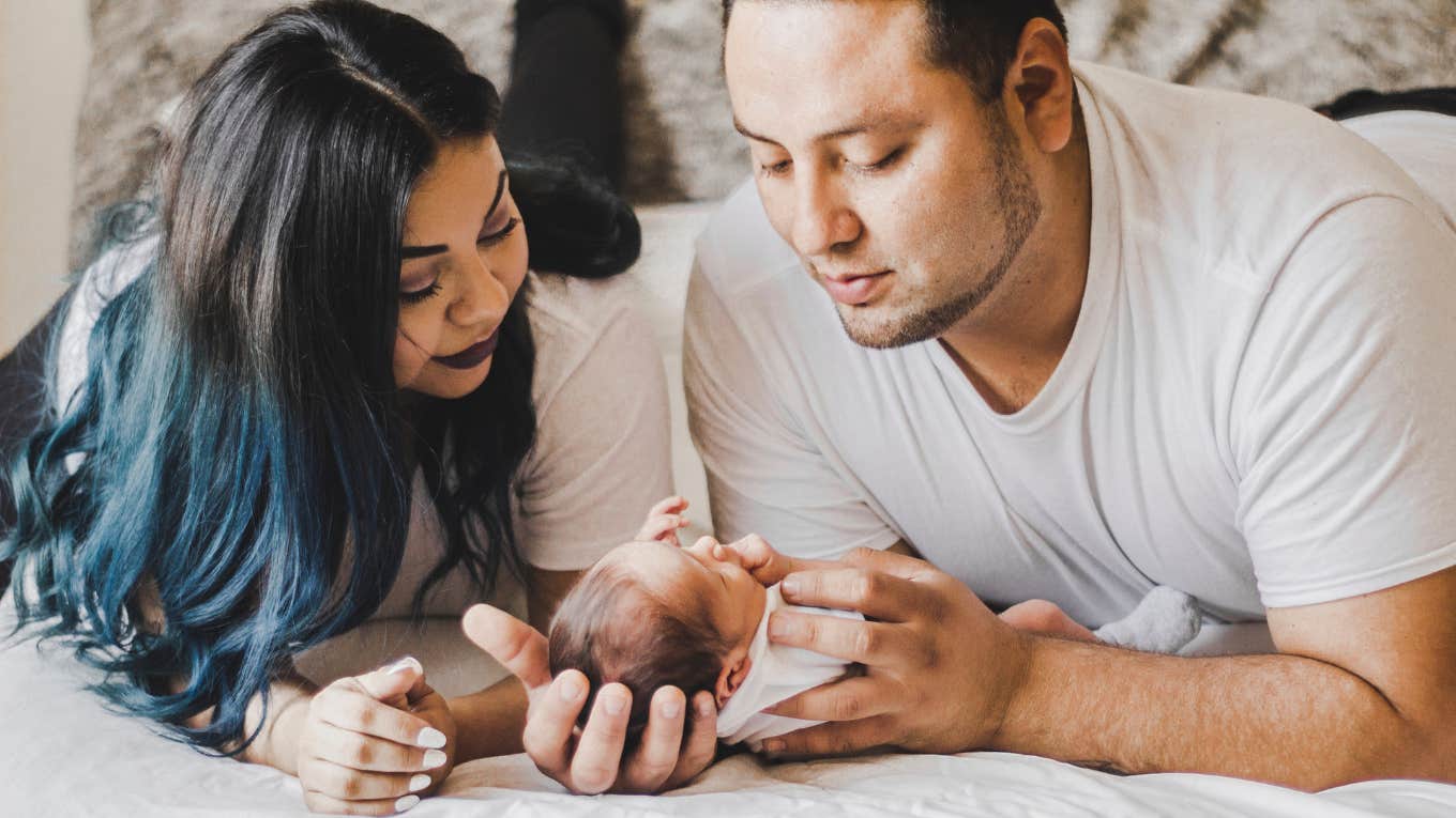 mom and dad with baby on bed