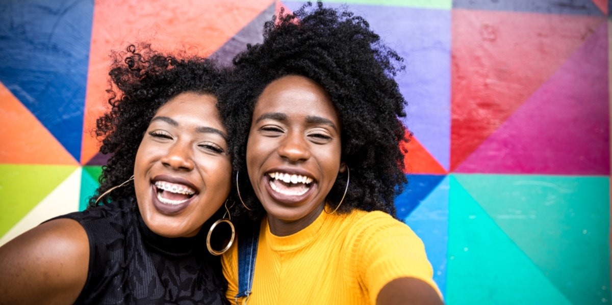 two women smiling in front of a colorful background