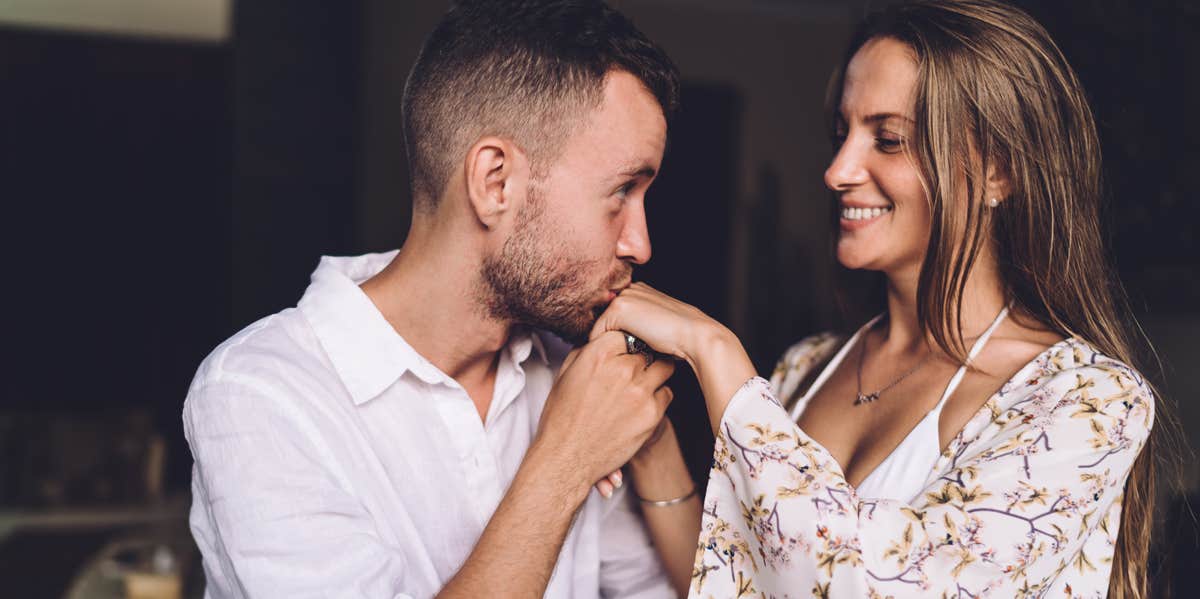 man kissing hands of woman