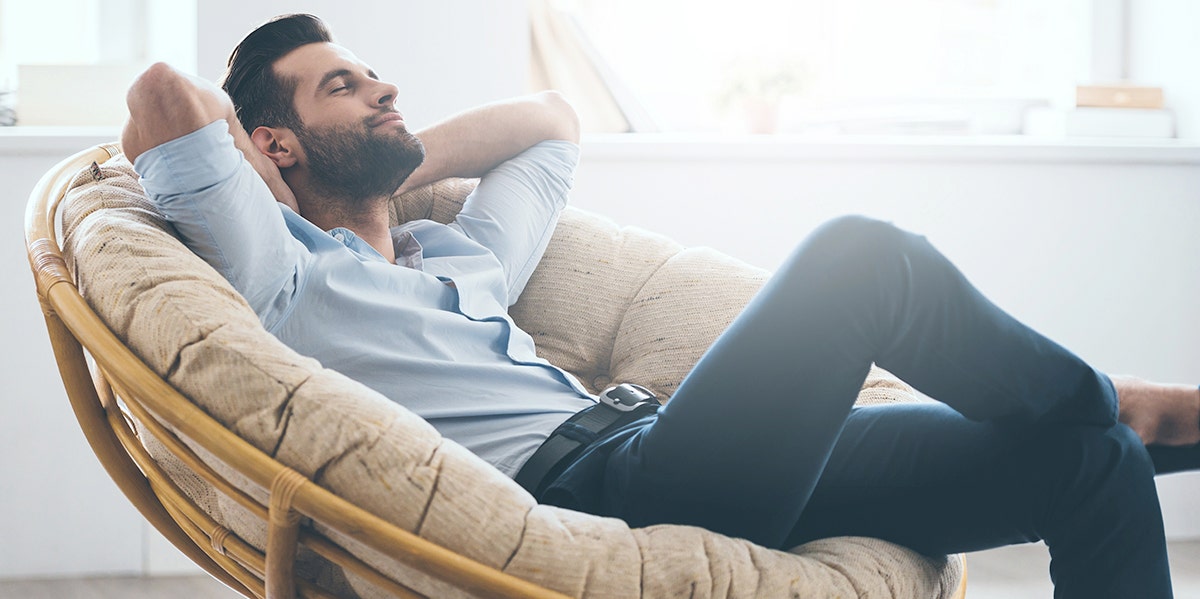 man on couch with hands behind head