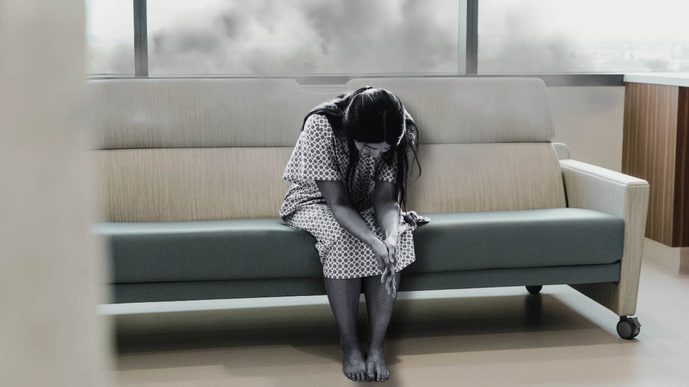 Woman sitting in hospital gown, sad