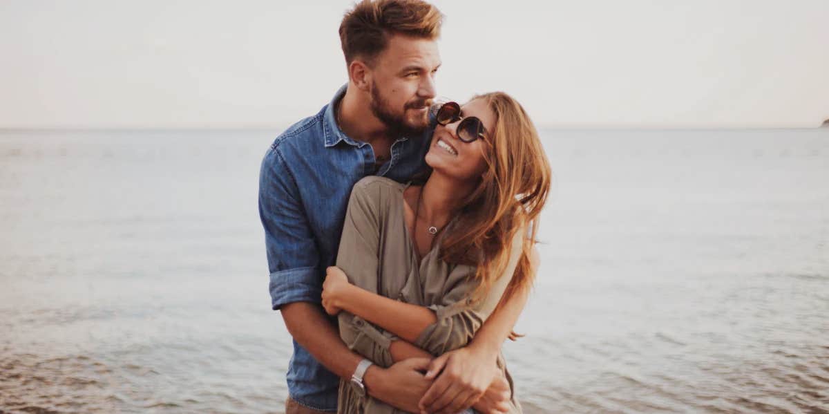 couple holding each other in front of the water