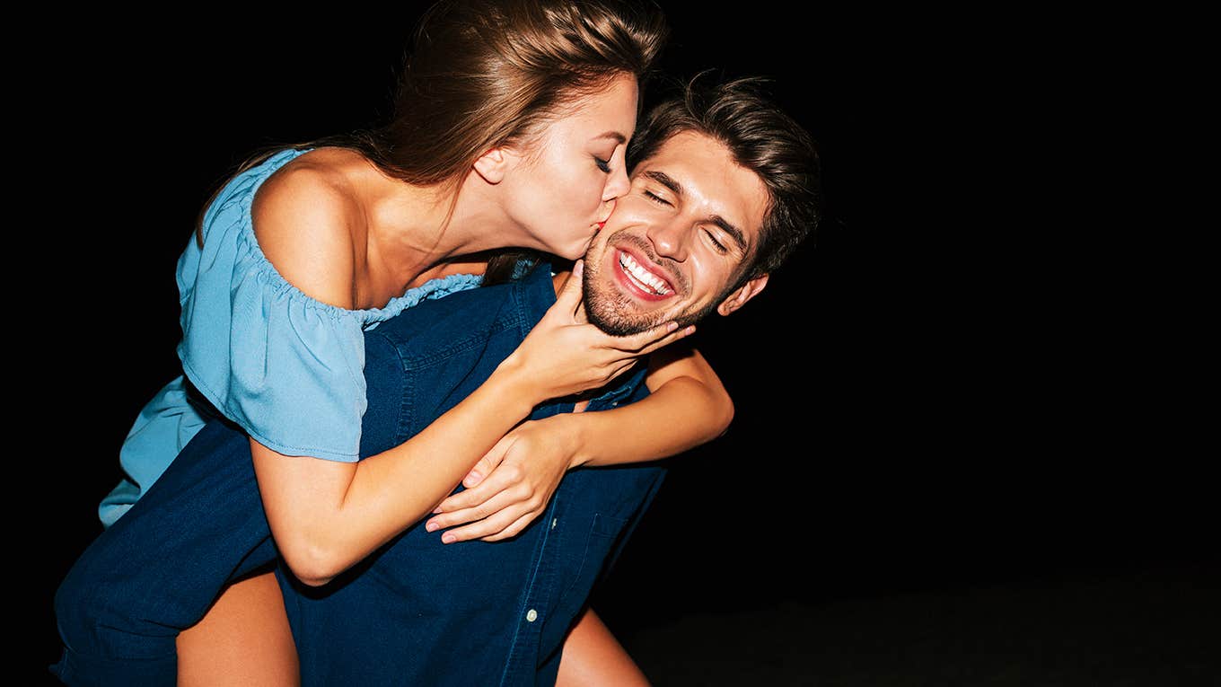 Happy young couple kissing and having fun on the beach at night
