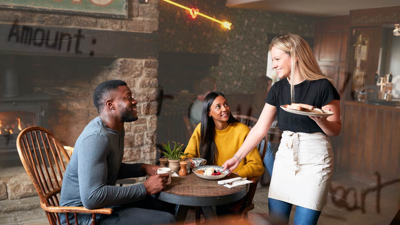 Couple at restaurant, waitress serving them food