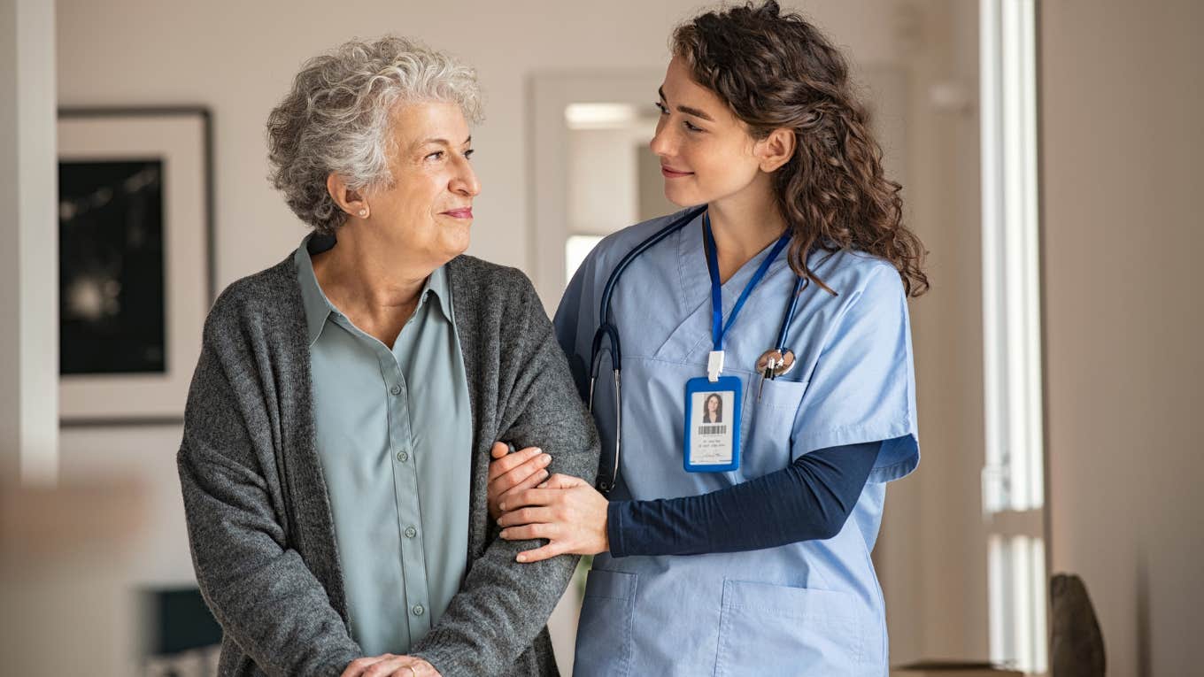 Nurse assisting her old woman patient at nursing home.