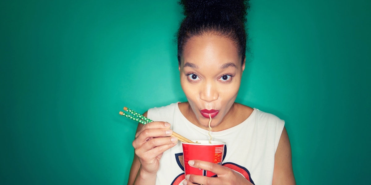 woman eating noodles with a green background