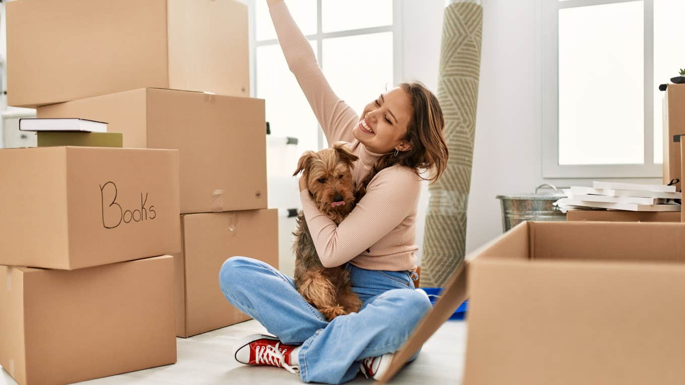 young woman moving into apartment sitting on floor with boxes