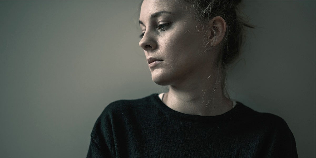 photo os sad woman in black shirt against wall