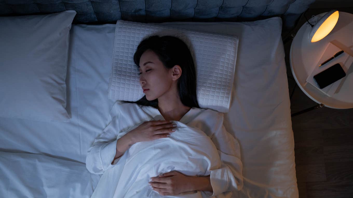 woman sleeping on her back with cell phone on nightstand