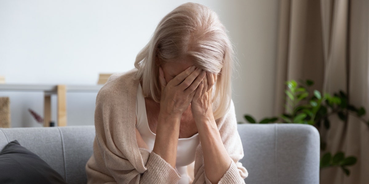 older woman covering her face