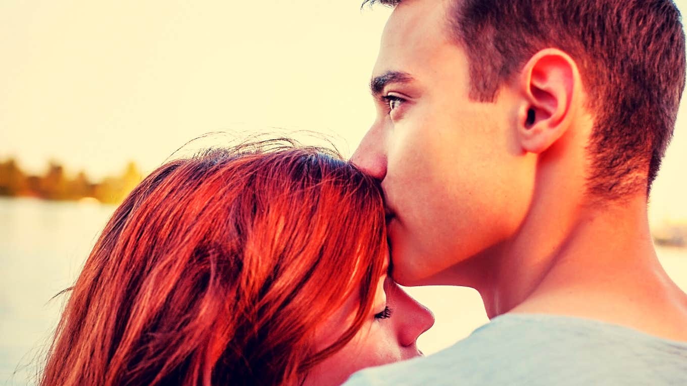 Handsome young man kissing the top of his girlfriend's head