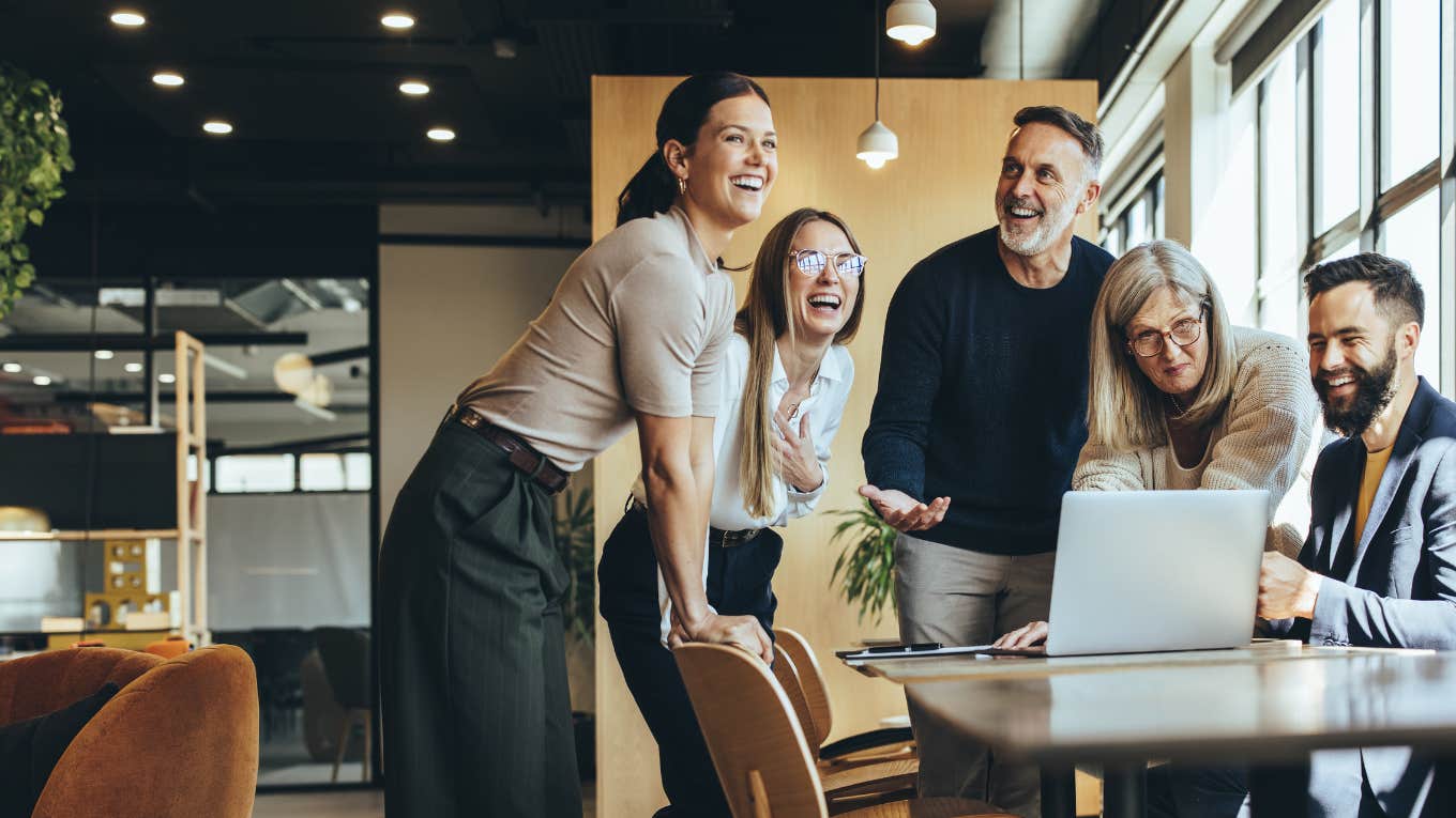 business people laughing while collaborating on a new project in an office.