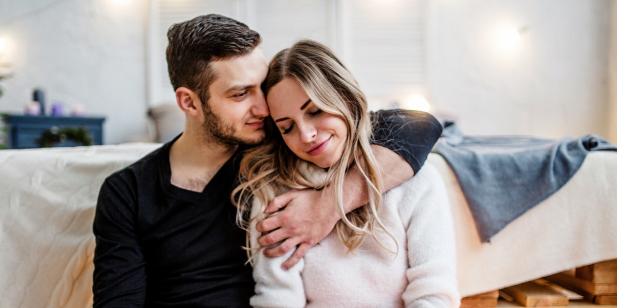 man and woman on couch cuddling