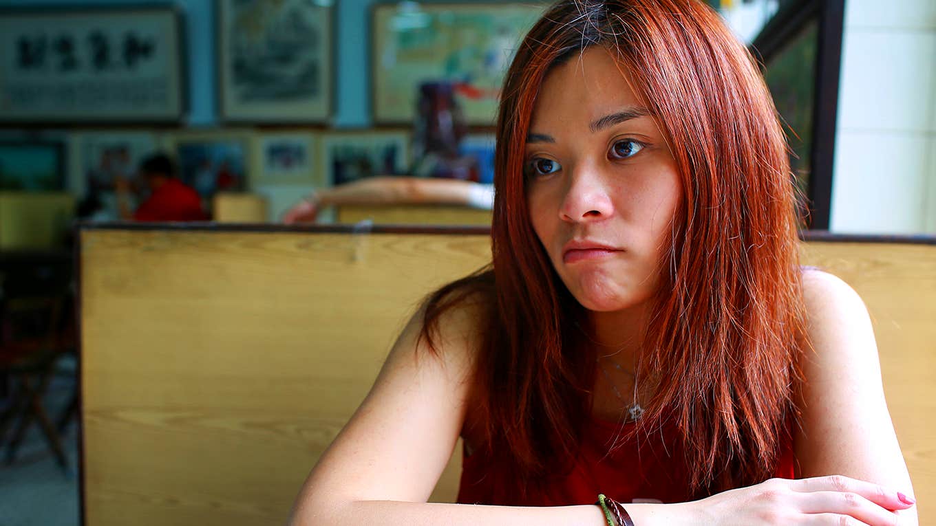 unhappy girl sitting in booth at restaurant