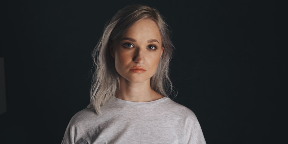 woman with blond hair staring forward black background