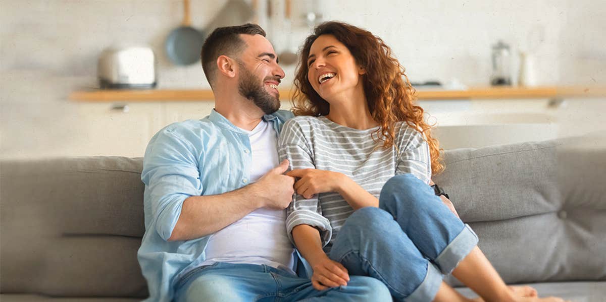 couple, smiling at each other, sitting on the couch