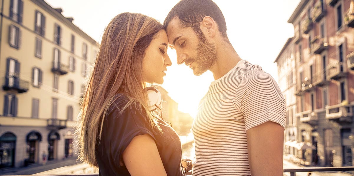 man and woman pressing foreheads together with sunset in background