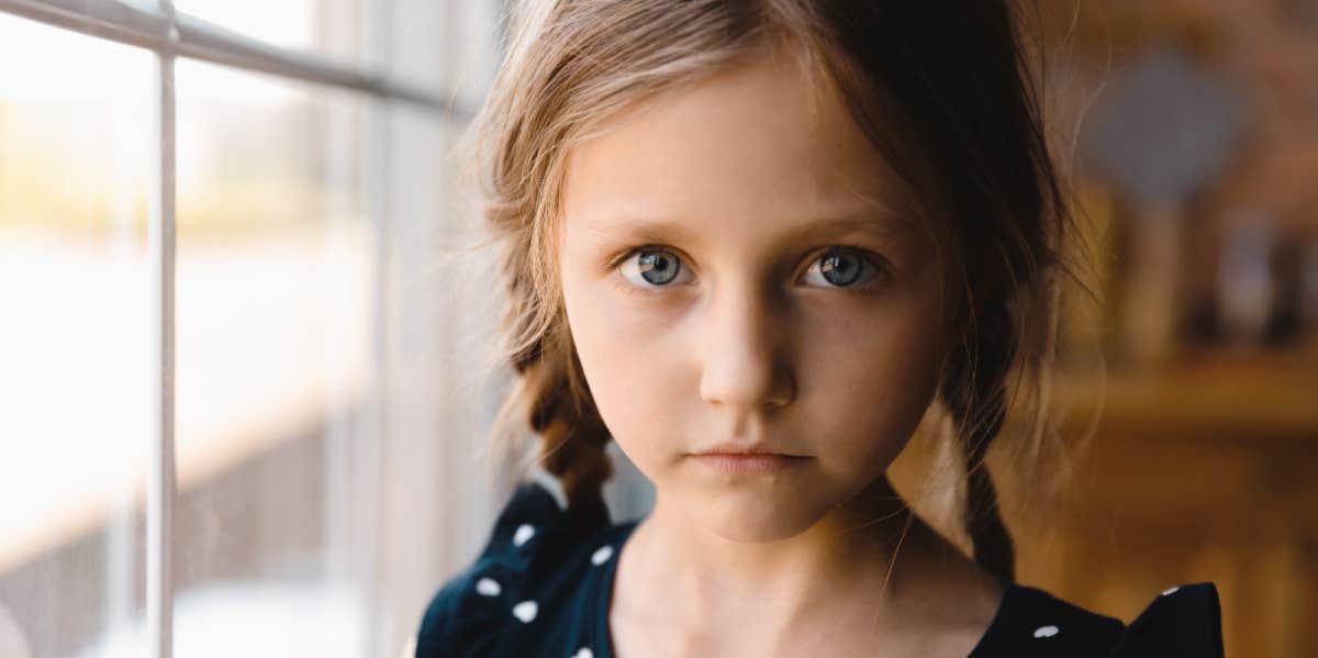 grade-school age girl in braids looks solemnly at camera