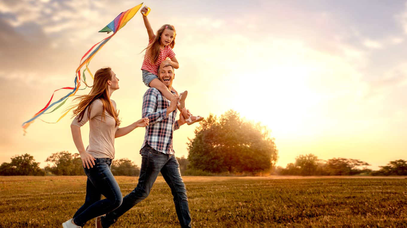 family running through field letting kite fly