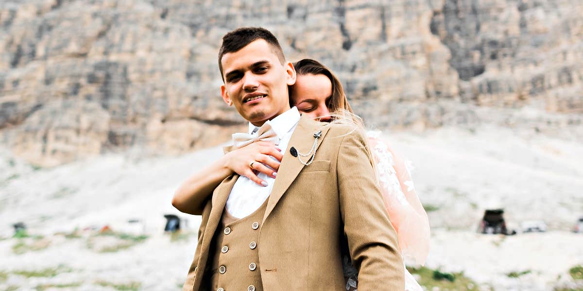 couple in dressy clothes standing in front of snowy cliff