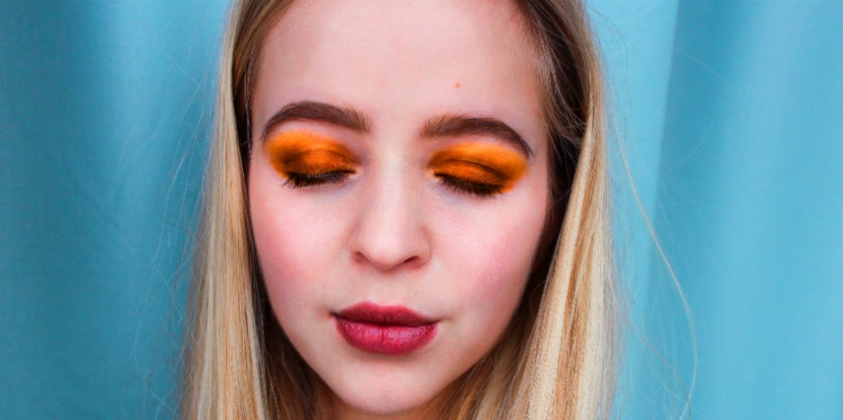 blond woman orange eyeshadow blue background