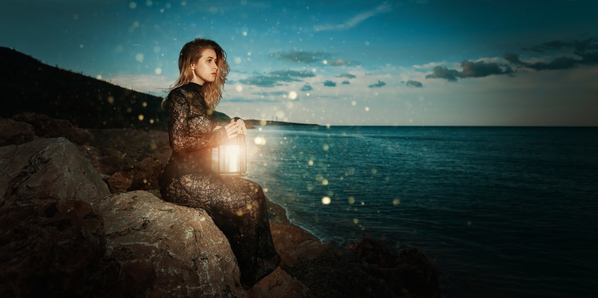 woman with lantern at night thinking of past life relationships