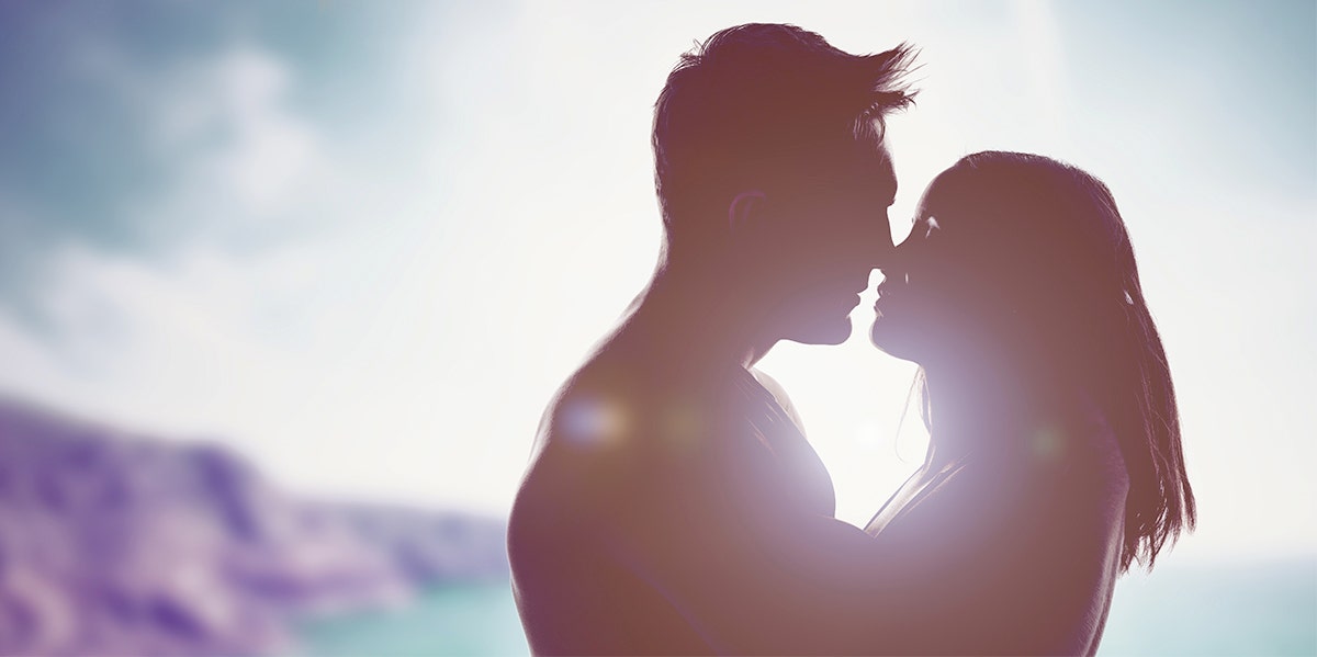 man and woman in shadow kissing in sunset