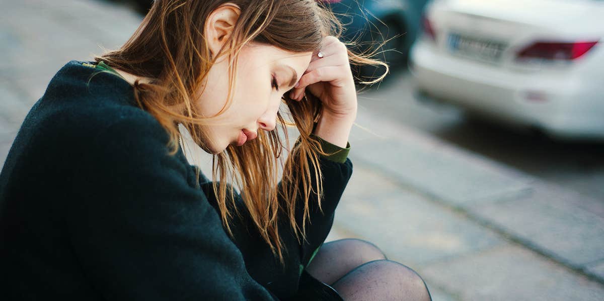 sad woman sits on the sidewalk