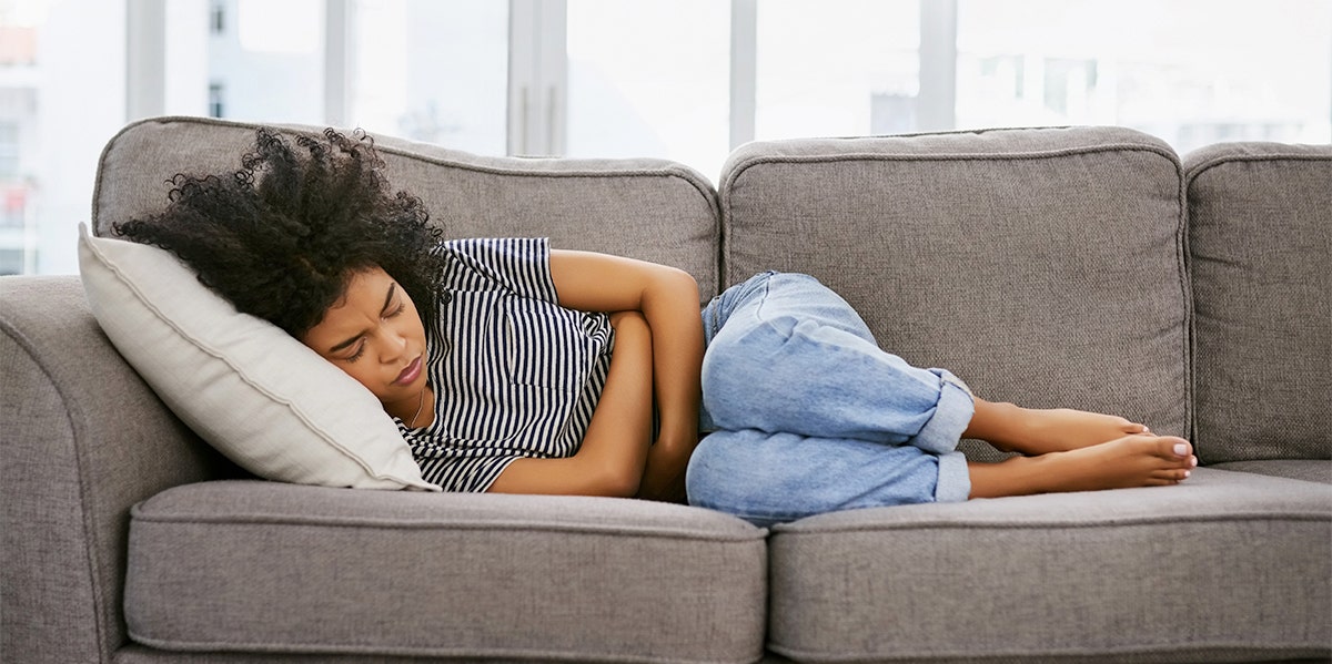What The Age You Start Menstruating Says About You woman on couch
