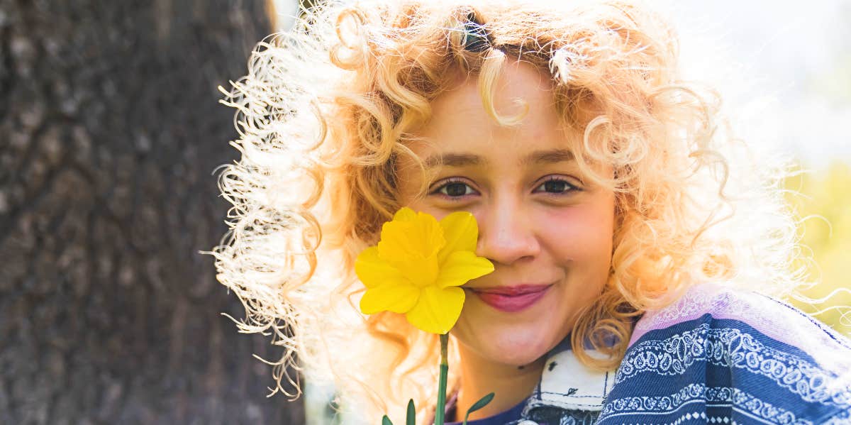 Woman holds up daffodil and smiles