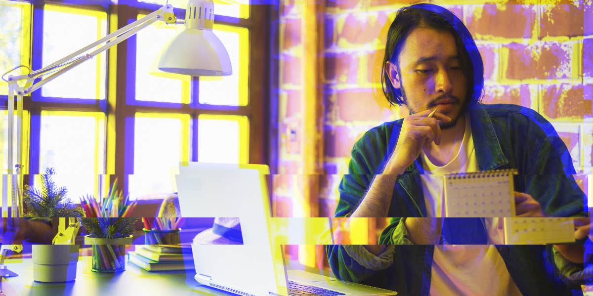 asian man sitting at a desk looking at a calendar