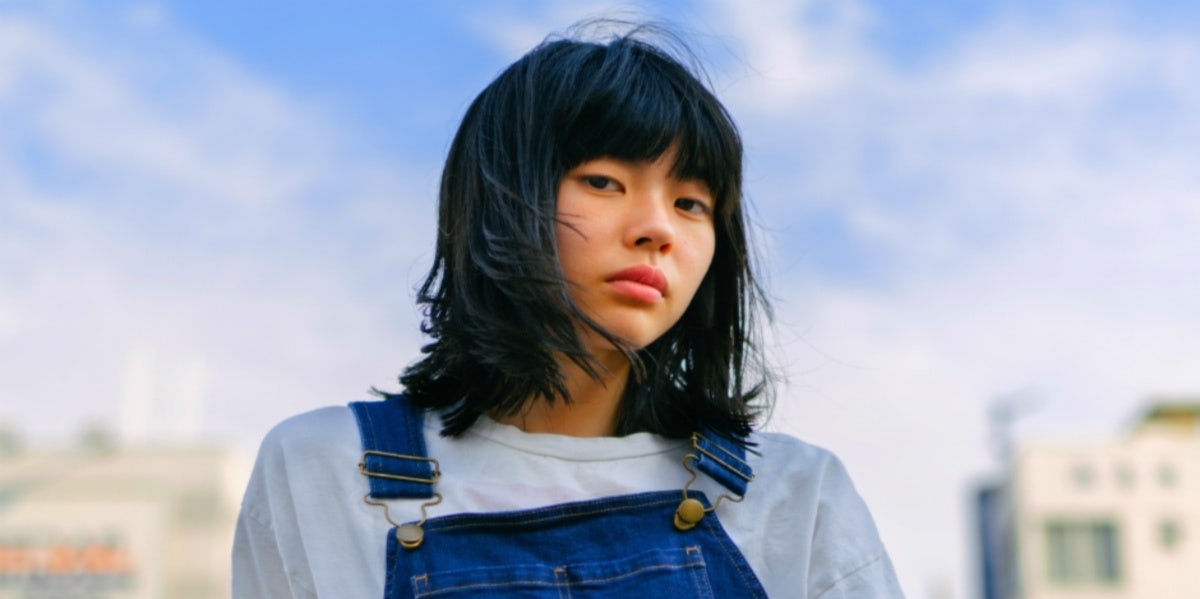 woman in overalls and bangs looking forward