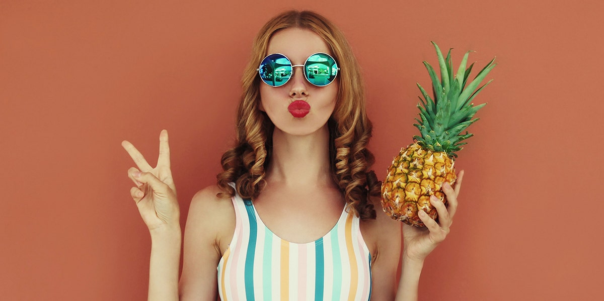 woman making peace sign duck face holding pineapple