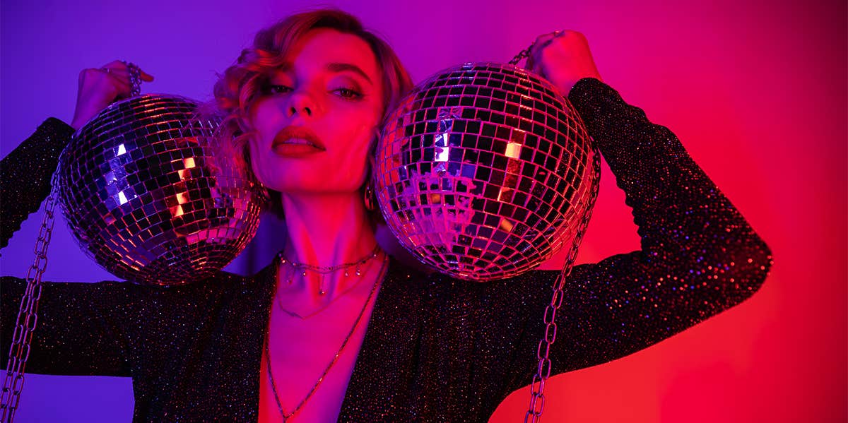 girl holding two disco balls in neon room