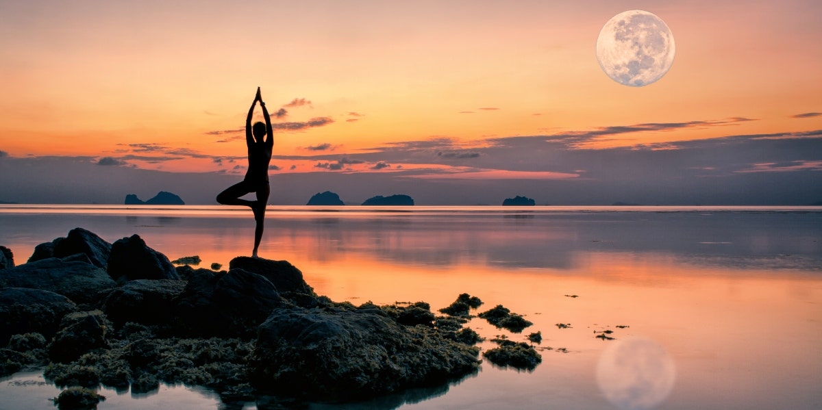 pink full moon woman doing a yoga pose by the water with the moon above